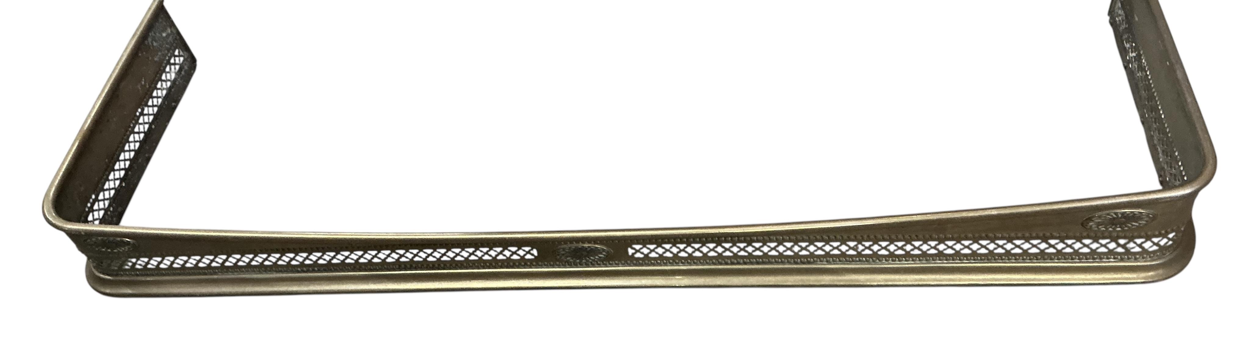 An Edwardian fender, a pair of wrought iron fire dogs and a set of brass implements